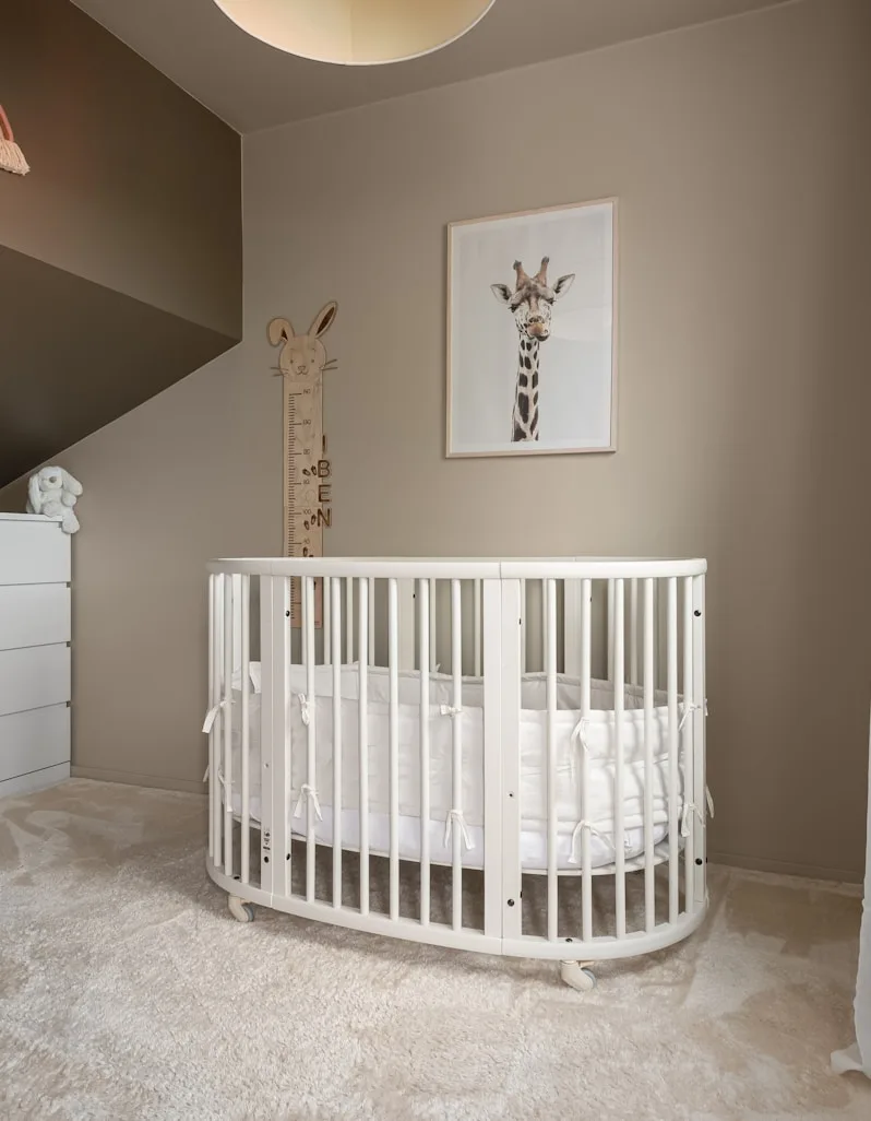 A nursery corner with a white crib and rocking chair