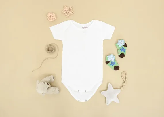 A baby onesie laid out with small knitted toys