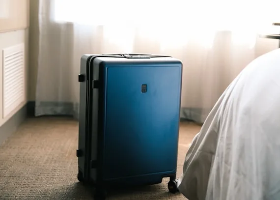 A packed suitcase sitting by the bed in natural window light, ready for a weekend away