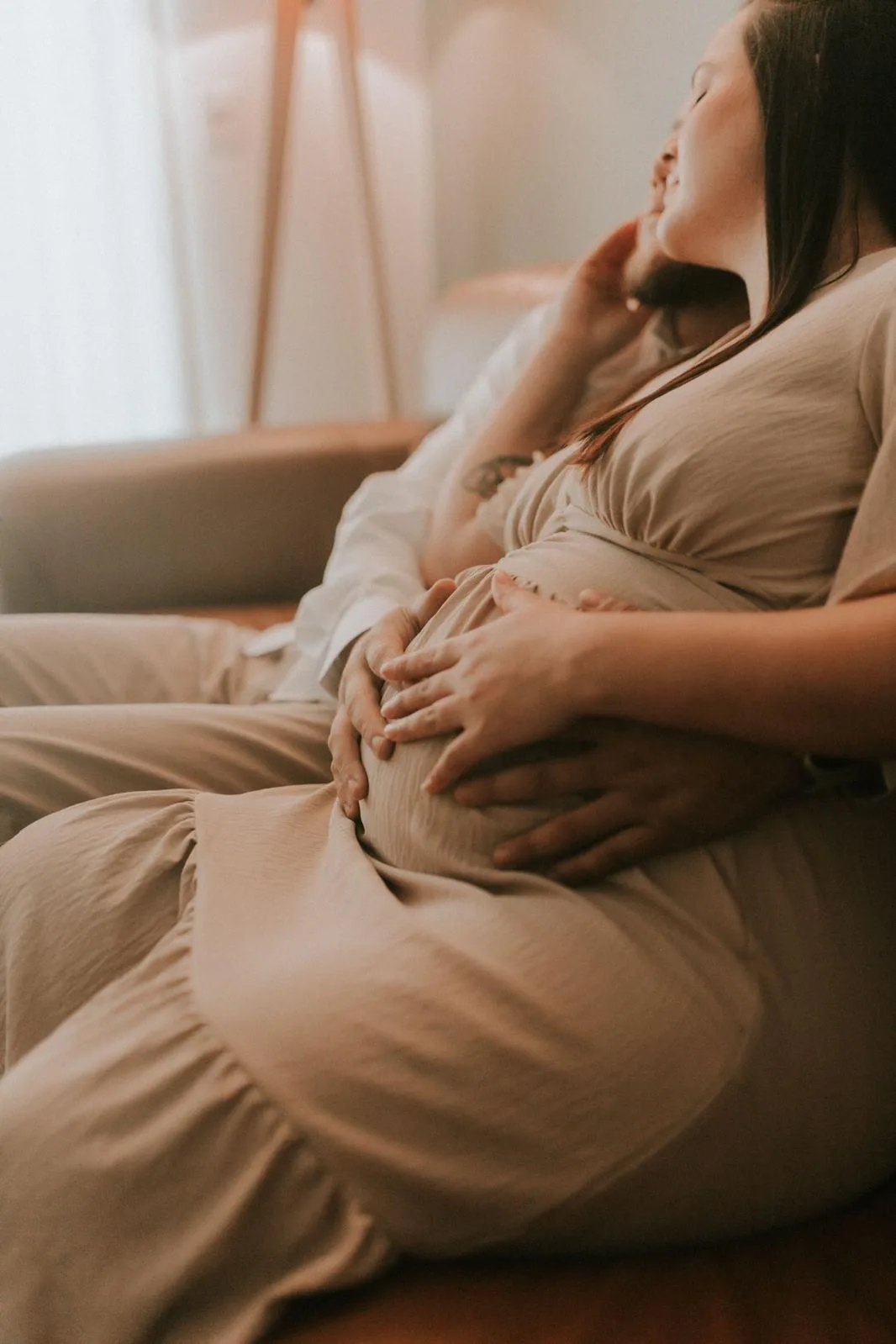 Close-up of a pregnant couple embracing, her hands resting over her belly