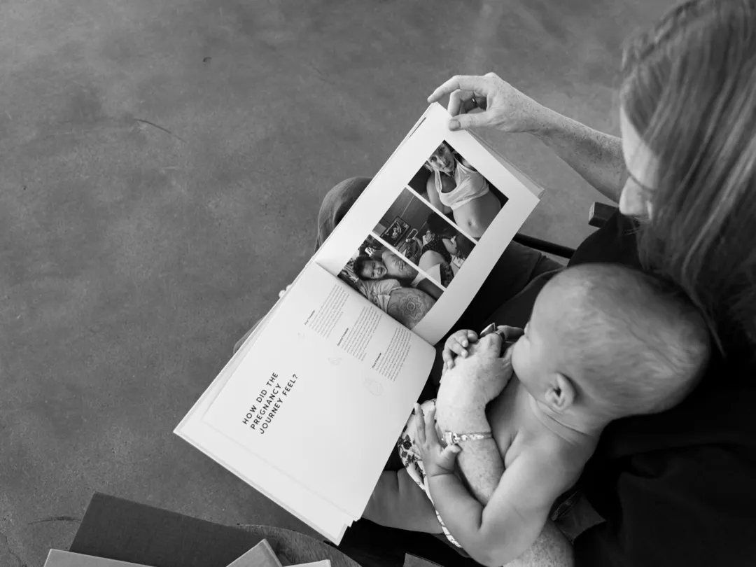A mother nurses her baby while looking back through her pregnancy journal pages.