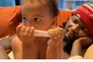 A child holding a positive pregnancy test beside their father